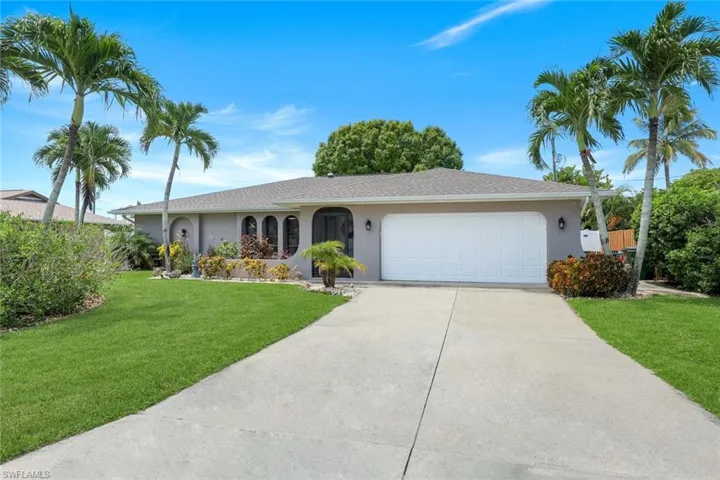 Single story home with stucco siding, driveway, an attached garage, and a front lawn