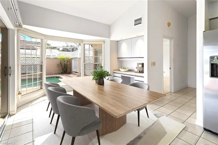 Dining space featuring light tile patterned flooring, high vaulted ceiling, and a desk