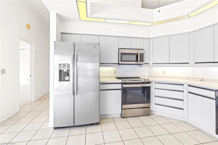 Kitchen with appliances with stainless steel finishes, light countertops, light tile patterned floors, and white cabinets