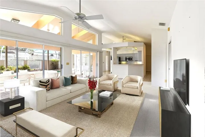 Living room with lofted ceiling, carpet flooring, and a ceiling fan