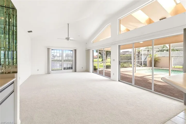 Unfurnished living room featuring high vaulted ceiling, light carpet, and a ceiling fan