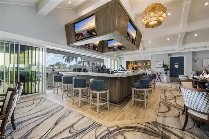 Bar area with high vaulted ceiling, beamed ceiling, recessed lighting, light wood-style floors, and hanging light fixtures
