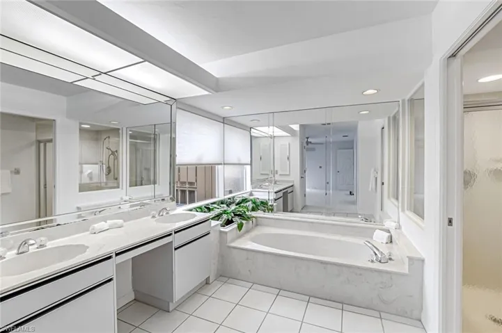 Bathroom featuring a stall shower, double vanity, a garden tub, light tile patterned floors, and recessed lighting