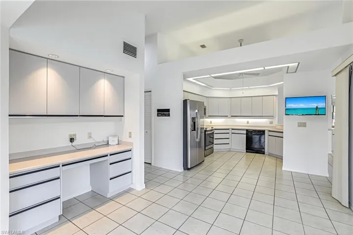 Kitchen with light countertops, stainless steel appliances, a tray ceiling, gray cabinets, and light tile patterned floors