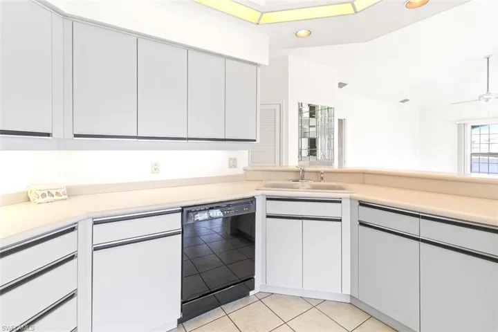 Kitchen with black dishwasher, light countertops, white cabinetry, and recessed lighting