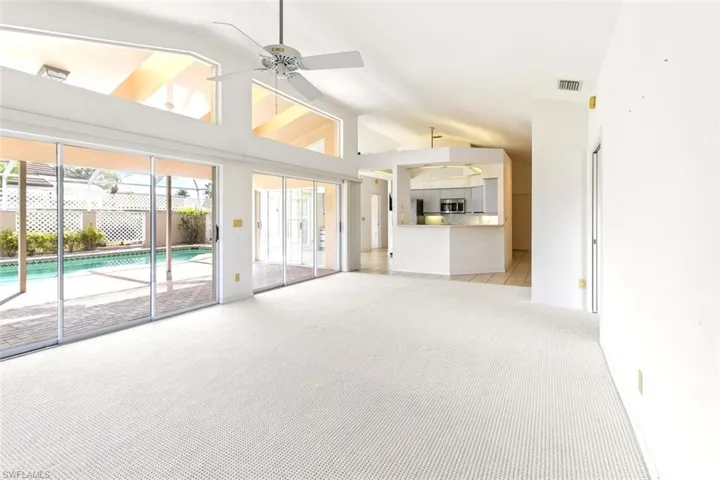 Unfurnished living room with lofted ceiling, light carpet, and a ceiling fan