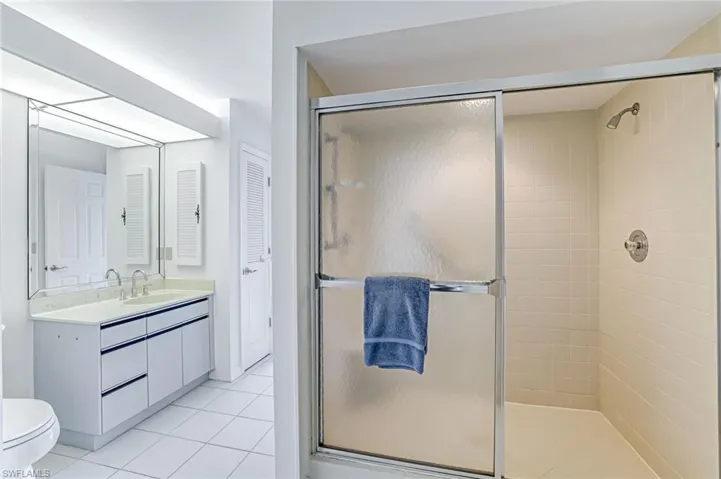 Bathroom featuring a shower stall, vanity, light tile patterned floors, and a closet