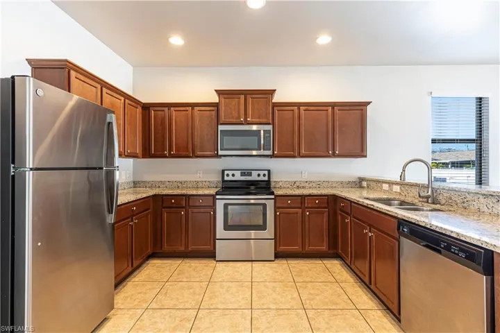 Kitchen featuring stainless steel appliances, light stone countertops, recessed lighting, a peninsula, and light tile patterned floors