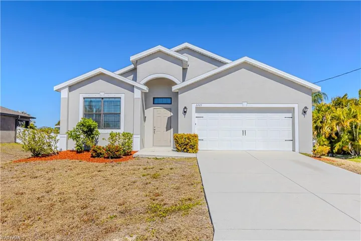 Ranch-style home with driveway, stucco siding, an attached garage, and a front yard
