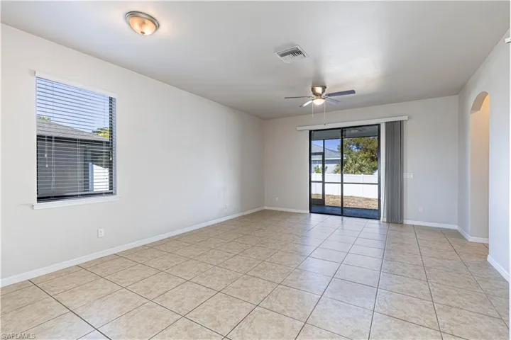 Spare room featuring arched walkways, a ceiling fan, plenty of natural light, and light tile patterned flooring
