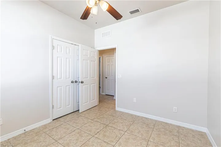 Unfurnished bedroom with ceiling fan, a closet, and light tile patterned flooring