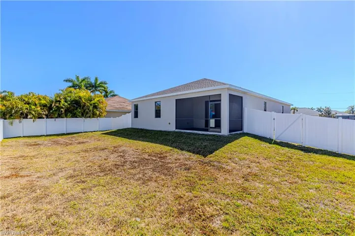 Rear view of property featuring a gate, a fenced backyard, stucco siding, and a sunroom