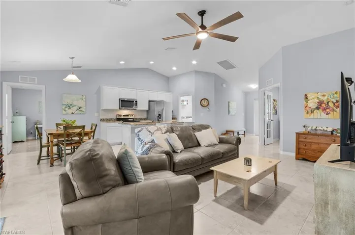 Living area featuring light tile patterned floors, visible vents, and a ceiling fan