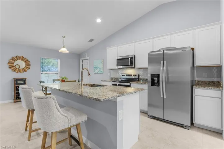 Kitchen with light stone countertops, visible vents, stainless steel appliances, and a sink