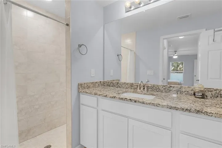 Ensuite bathroom featuring visible vents, a ceiling fan, ensuite bath, a tile shower, and vanity