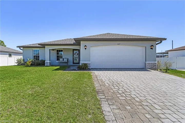Single story home featuring a garage, decorative driveway, fence, and stucco siding