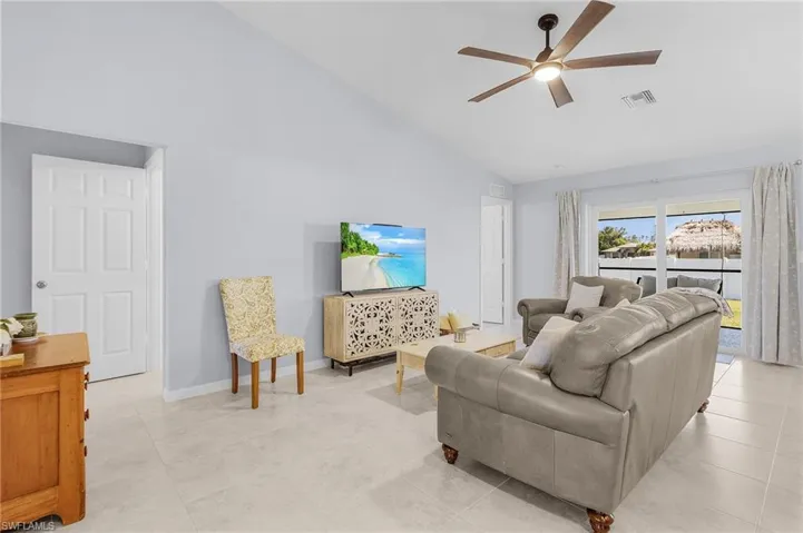 Living area featuring high vaulted ceiling, ceiling fan, visible vents, and baseboards