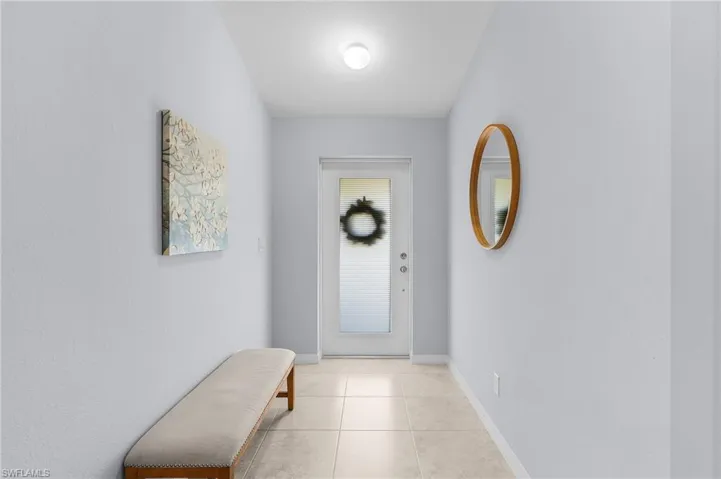 Doorway to outside featuring light tile patterned floors and baseboards