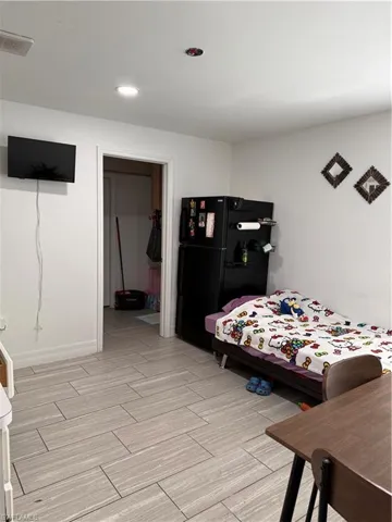 Bedroom with freestanding refrigerator, wood finish floors, and a spacious closet