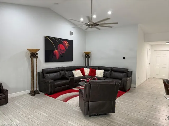 Living room with wood finish floors, a ceiling fan, and lofted ceiling