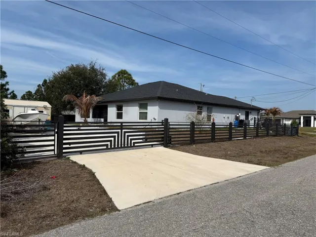 View of side of property featuring a fenced front yard, a gate, and stucco siding