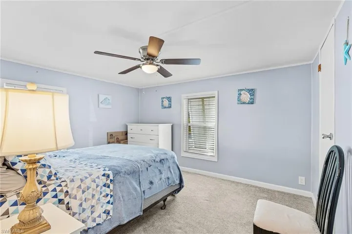 Carpeted bedroom with ceiling fan and crown molding