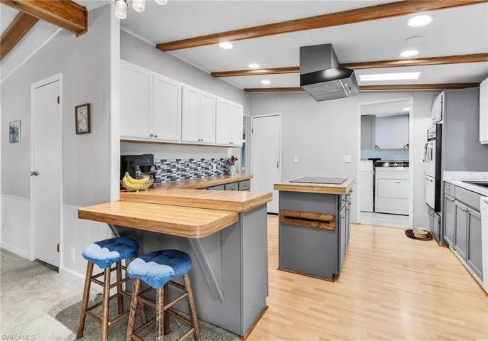 Kitchen with a breakfast bar, wood counters, a peninsula, tasteful backsplash, and extractor fan