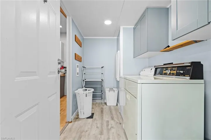 Laundry area featuring light wood-style flooring, recessed lighting, cabinet space, and washer and dryer