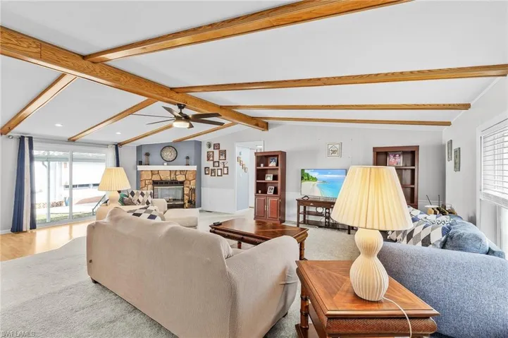 Living room featuring healthy amount of natural light, a fireplace, and a ceiling fan