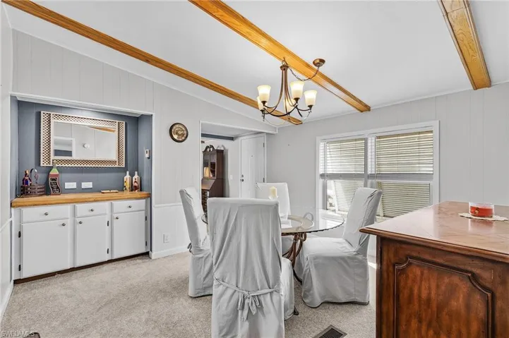 Dining space with a chandelier, light carpet, and beautiful beams
