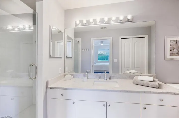 Ensuite bathroom featuring a shower stall, vanity, and a closet