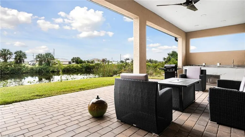 View of patio / terrace featuring grilling area, a sink, a ceiling fan, and a water view