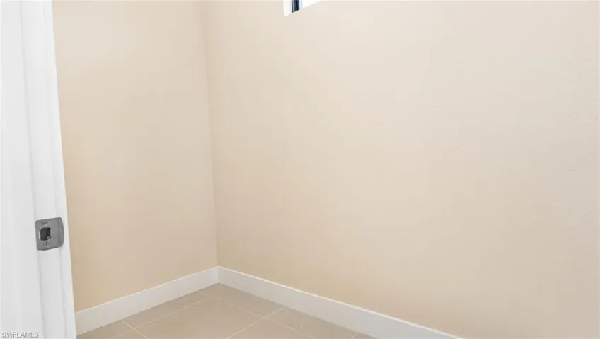 Laundry area with light tile patterned floors, laundry area, and baseboards