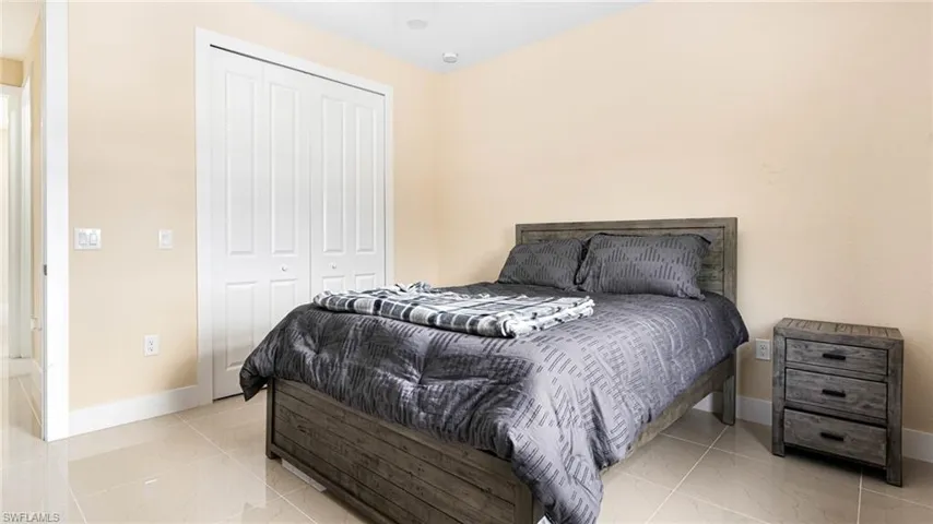 Bedroom featuring a closet, marble finish floor, and baseboards