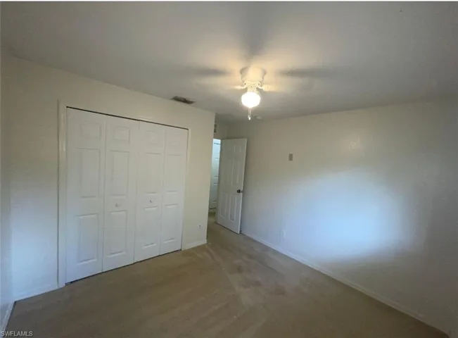 Unfurnished bedroom featuring carpet flooring, a closet, and ceiling fan