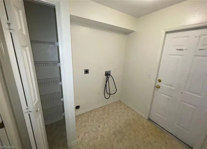Clothes washing area featuring electric dryer hookup and light tile flooring