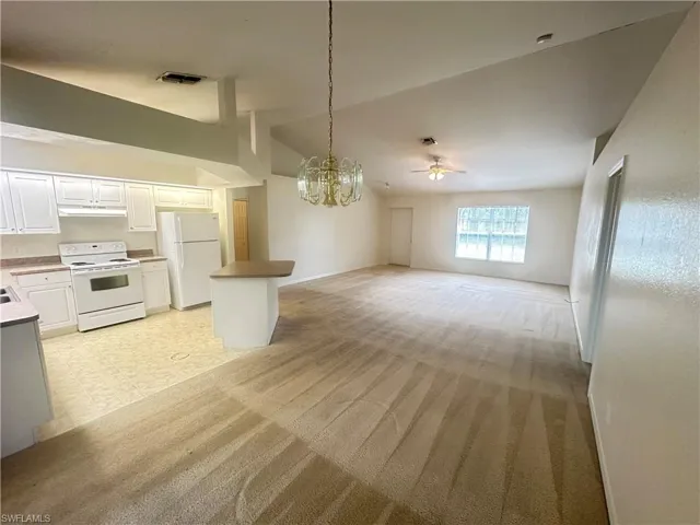 Kitchen featuring decorative light fixtures, ceiling fan with notable chandelier, white cabinetry, white appliances, and light tile floors