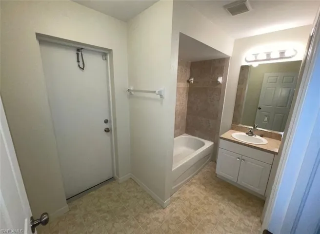 Bathroom with tile floors, tiled shower / bath combo, and large vanity