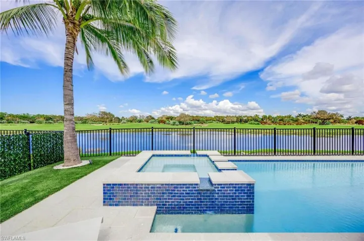 View of swimming pool featuring a water view, an in ground hot tub, and a lawn