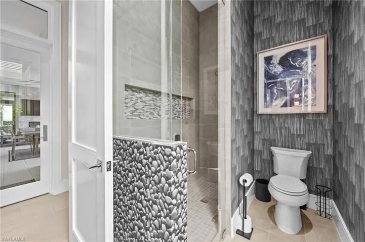 Bathroom featuring toilet, tile patterned flooring, and an enclosed shower