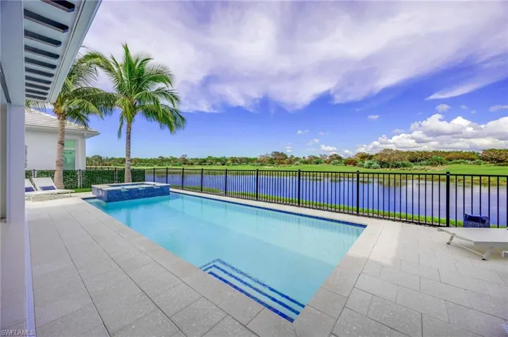 View of swimming pool featuring a patio area, an in ground hot tub, and a water view