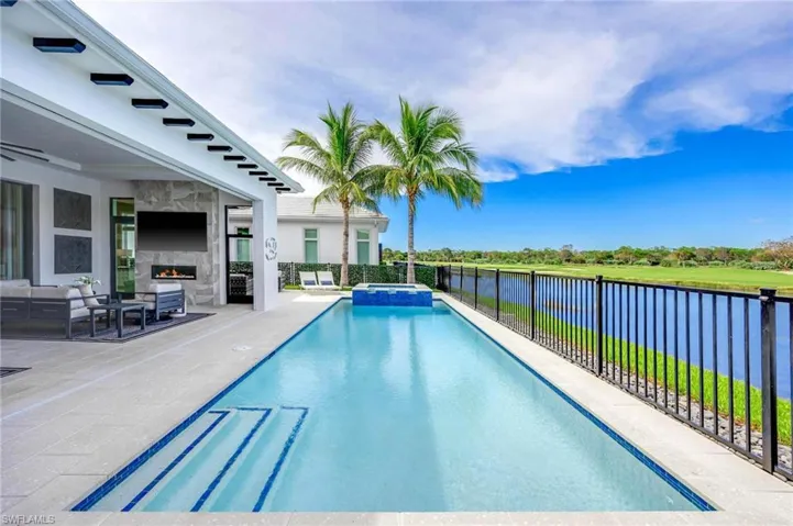 View of pool featuring a patio area, an outdoor living space with a fireplace, and a water view