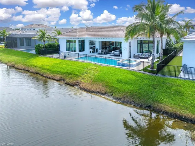 Back of property with a patio, a fenced in pool, a lawn, and a water view