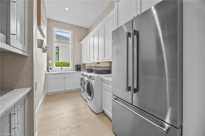 Laundry area featuring sink, independent washer and dryer, light hardwood / wood-style floors, and cabinets