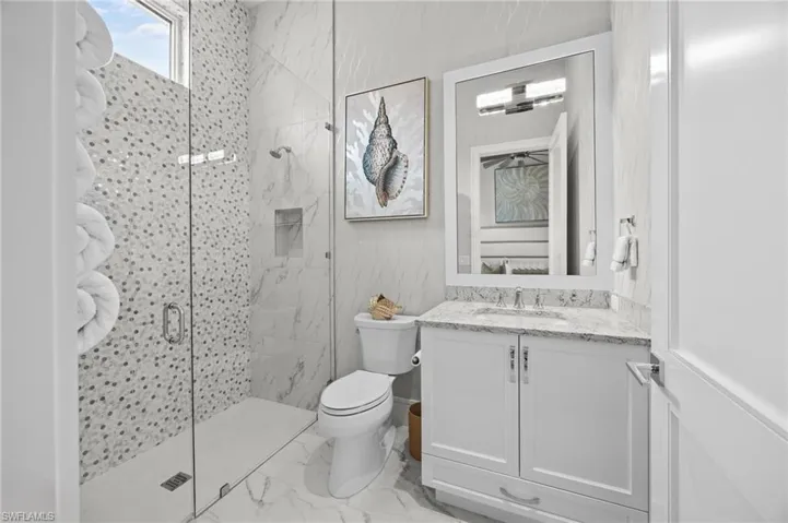 Bathroom featuring vanity, toilet, and a shower with door