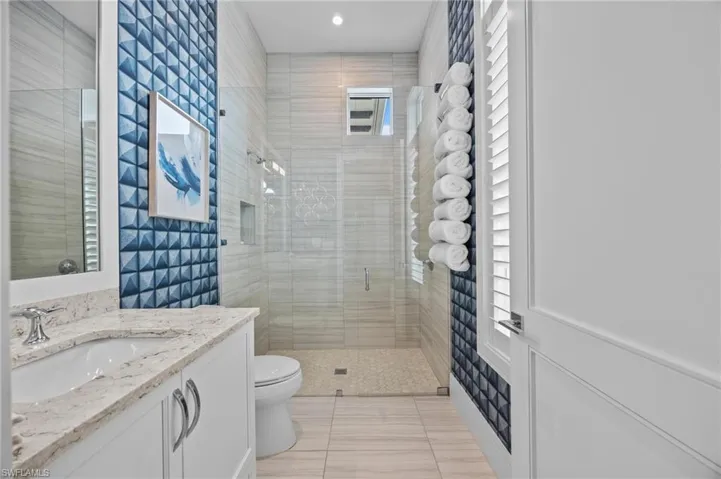 Bathroom featuring vanity, tile patterned flooring, toilet, and walk in shower