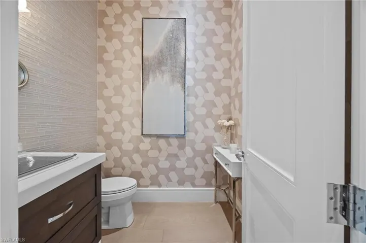 Powder bathroom featuring toilet, vanity, and tile patterned flooring