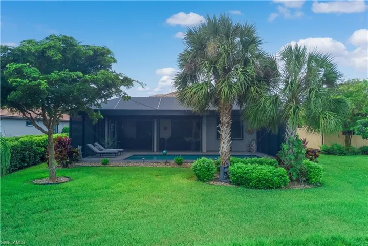 Rear view of property with a patio, a lawn, and a lanai