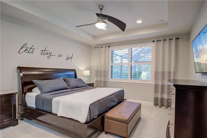Bedroom with a raised ceiling, carpet being replaced,  a ceiling fan, window treatments, and recessed lighting