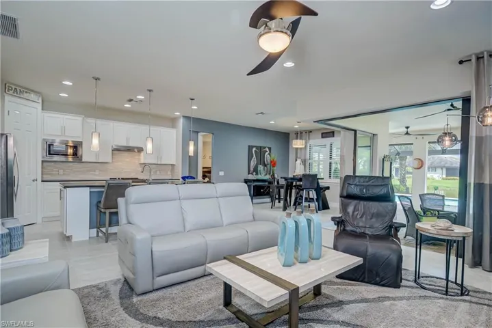Open living room & dining for entertaining-  with recessed lighting, a ceiling fan, and light tile patterned floors. Zero edge doors make indoor/outdoor flow easy to the lanai area and pool